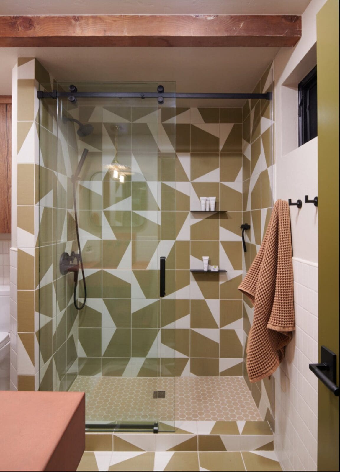 Mid-century modern bathroom with geometric tile and copper sink in renovated 1970s cabin