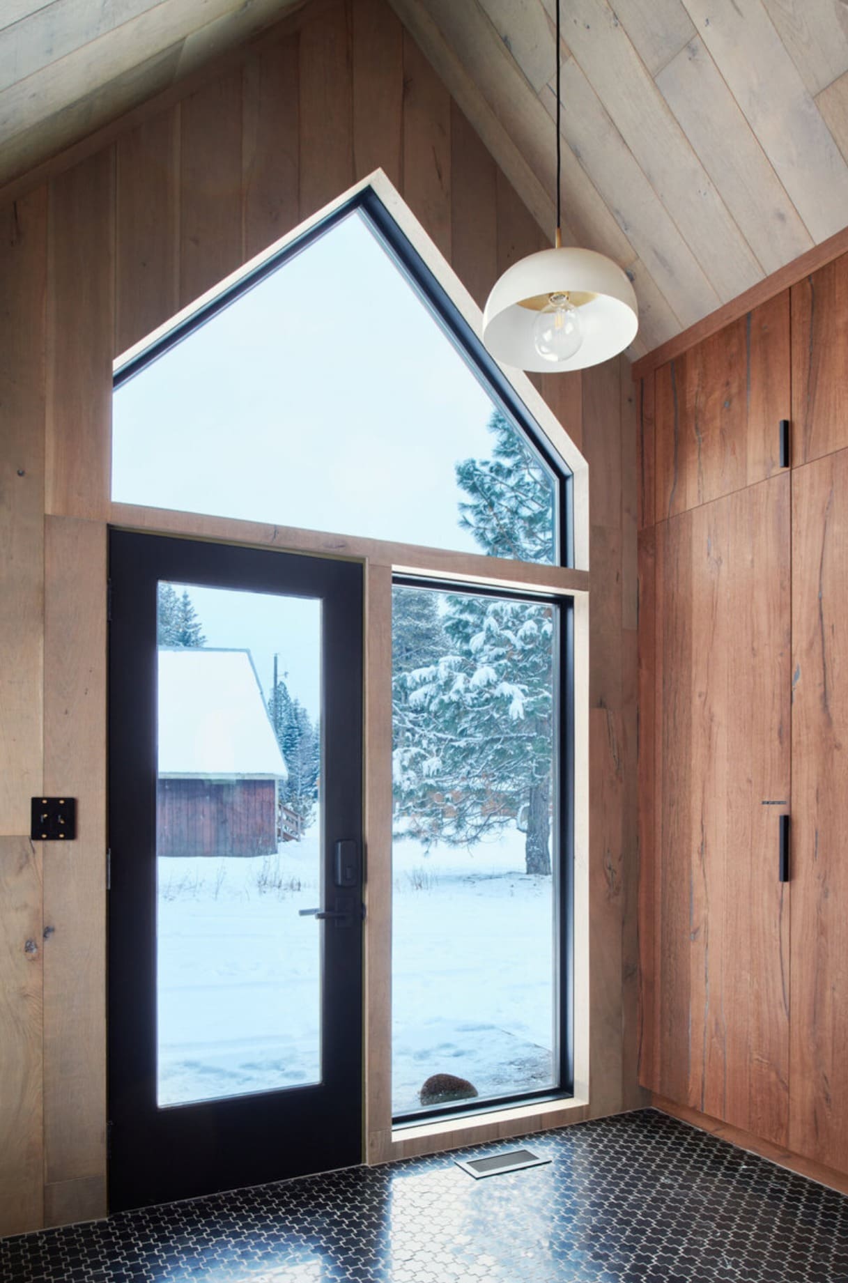 Dramatic entry with vaulted ceiling and black-framed windows maximizing natural light