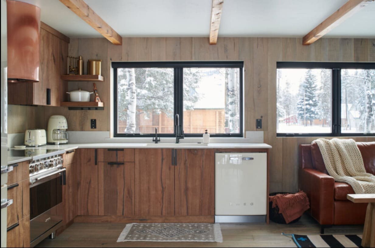 Warm ambient lighting creates inviting atmosphere in open concept cabin kitchen and living area