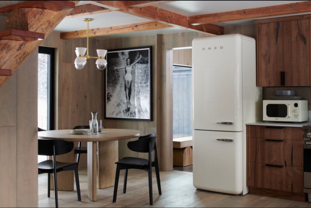 Retro SMEG refrigerator and mid-century dining area in cozy cabin design kitchen