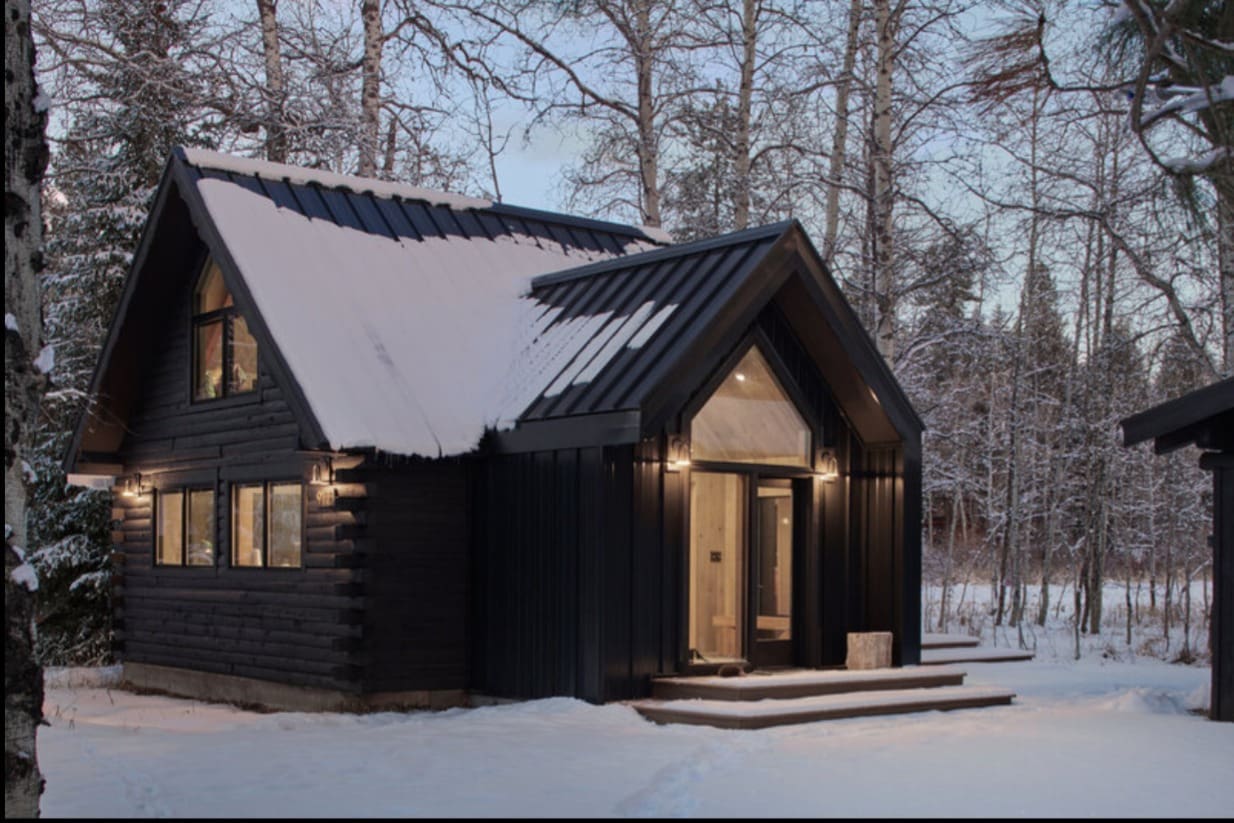 Swissentury cabin exterior showcasing black stained log structure and modern entrance in McCall